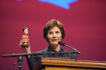 Laura Bush, former first lady of the United States, holds up a bobble head doll of herself while telling a funny story at the 13th annual Scholarship Banquet.  - Photo by Morris Abernathy