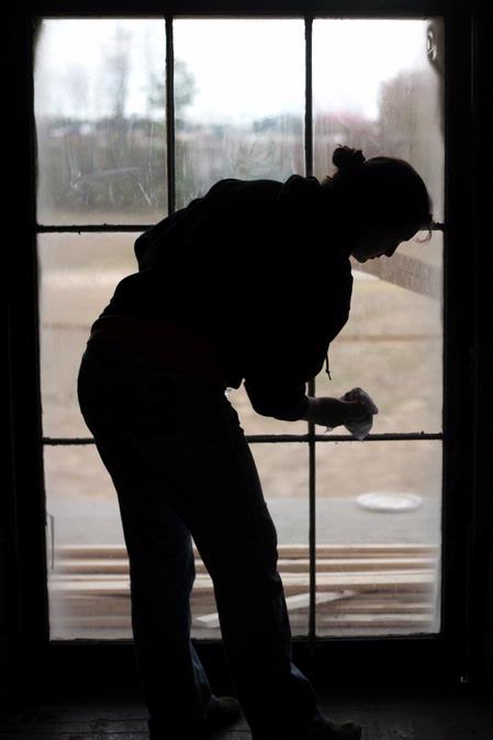 Megan Winters, junior history major, scrubs a window of the Neil House, an 1800s home that is currently being restored at Casey Jones Village. The home was recently moved to Jackson from Trenton, TN. History faculty and students helped with the restoration process as part of Campus and Community Day.  - Photo by Kristi McMurry Woody