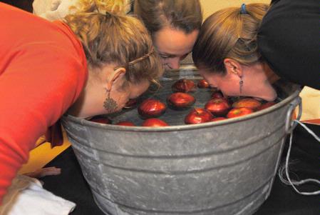 Hannah Mahoney, sophomore nursing major, Rebecca Blevins, freshman pre-med major, and Samantha Adams, sophomore public relations major, bob for apples during the fall festival put on by the BSNF to raise money for nursing students going on GO trips. - Photo by Victoria Stargel