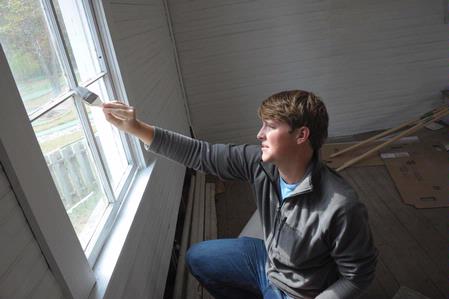 Cale Little, sophomore history major, helps paint the trim on a window of an historic church located in Casey Jones Village. The history department helped with restoring two buildings as a part of Campus and Community Day.  - Photo by Morris Abernathy