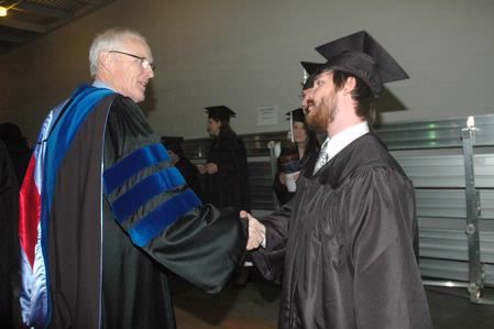James Patterson, associate dean of the School of Theology & Missions, shakes the hand of William Barnett as the students line-up for graduation. - Photo by Beth Spain