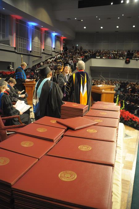 Tim Smith, dean of the school of nursing, calls the names of December nursing graduates as David S. Dockery, president of the university, hands the graduates their diplomas.  - Photo by Morris Abernathy