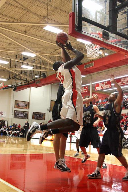 Roland Banhoro, senior center, goes up for a basket against Bethel University defenders. The Bulldogs won the game 77-75.  - Photo by Ebbie Davis