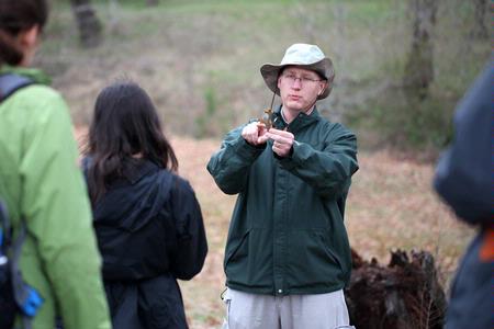 Andy Madison, associate professor of biology, shows his conservation biology students a leaf from a nearby tree during a field trip to the West TN Research & Education Center. - Photo by Kristi McMurry Woody