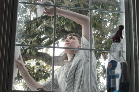Senior Jeremy DeMoss, biology major, washes windows at the Care Center, which provides shelter to women and children in the Jackson area. Students spent the day doing cleaning and yardwork projects for the center. - Photo by Lindsay Stavish