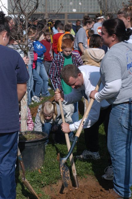 Softball & Volleyball Coach Brian Dunn digs a hole for a new tree at Parkview Montessori with Assistant Coach Jennifer Sabourin and several of their players during Day of Remembrance 2003. - Photo by Jonathan Blair