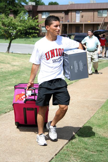 Brian Castro, sophomore athletic training major, carries a student's things during New Student Move-in. - Photo by Deanna Santangelo