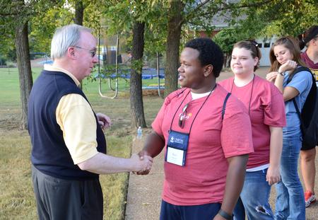 David S. Dockery, president of the university, shakes hands with freshman Kael Moore during an ice cream social held outside the Dockery's home. - Photo by Jacob Moore