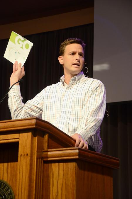 Ben Mandrell, senior pastor of Englewood Baptist Church, references a brochure about GO mission trips during chapel and mentions the importance and blessings of mission work. - Photo by Jacob Moore