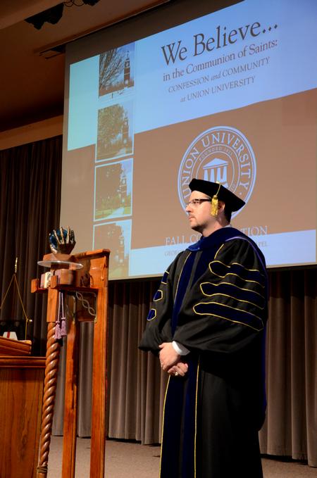 Keith Bates, associate professor of history and faculty member of the year, stands on stage as other faculty members file in to Convocation at the beginning of the semester. - Photo by Ebbie Davis