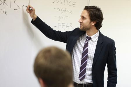 Jason Crawford, assistant professor of English, writes on the board as he lectures about tragedy.  - Photo by Kristi McMurry Woody