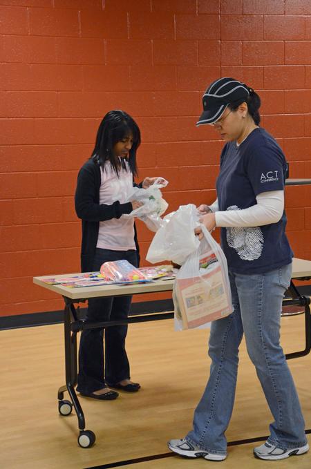 Liane Gozmao, senior biology major, and Haelim Allen, assistant professor of art, unpack bags of supplies for Operation Christmas Child during Campus and Community Day.  - Photo by Anne Richoux