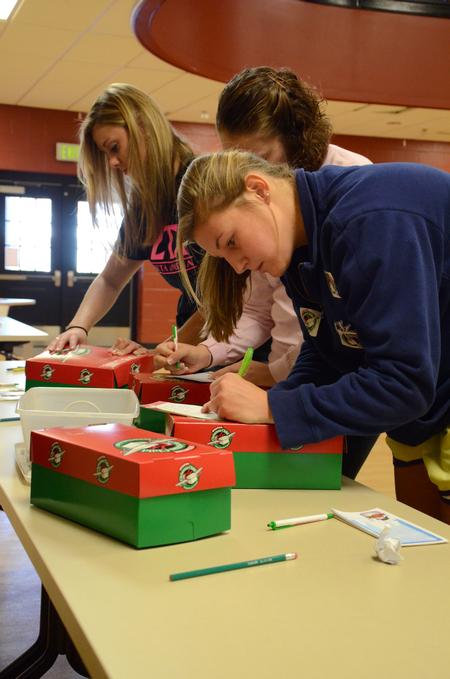 Morgan Roth (front), freshman nursing major, fills out a form for an Operation Christmas Child box during Campus and Community Day. - Photo by Anne Richoux