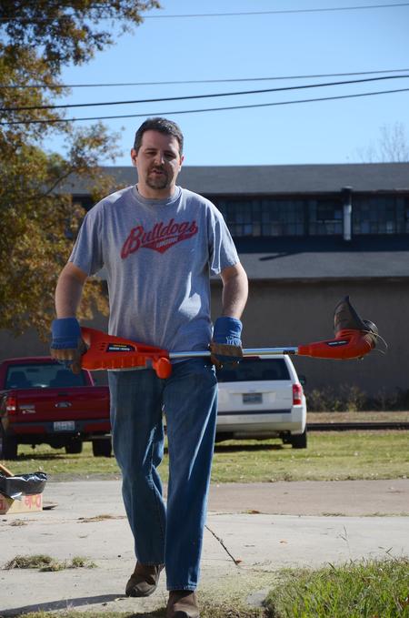 Keith Bates, associate professor of history, uses a weed eater outside of the Bemis Mill Village Museum during Campus and Community Day.  - Photo by Zac Calvert