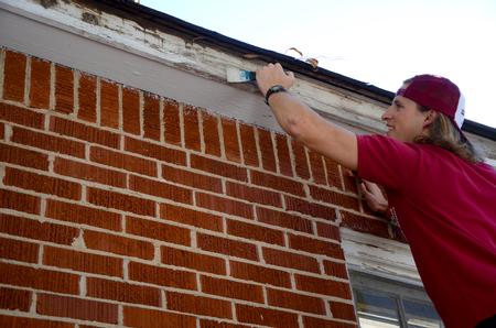Jake Ryan, senior business administration major, prepares to repaint the trim of a local elderly woman's home during Campus and Community Day. - Photo by Ebbie Davis