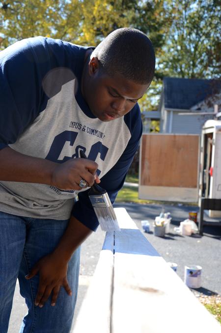 James Barbee, junior elementary education major, paints a railing at a Jackson home during Campus and Community Day. - Photo by Ebbie Davis