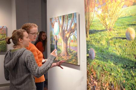 Senior art majors Lori Landon and Rachel Moore discuss one of Lisa D. Line's paintings during an art reception.  - Photo by Anne Richoux