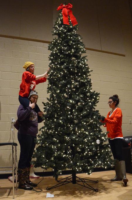 Kyleigh Carter (top left), sophomore social work major, Amiee Brassart, sophomore elementary education major, and Claudia Velasco, junior accounting major, help set up a Christmas tree in the Bowld Student Commons during Deck the Halls.  - Photo by Anne Richoux