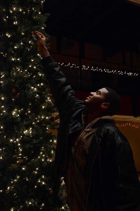 Antoine Hall, senior DMS major, hangs an ornament on a Christmas tree during Deck the Halls, a residence life event to celebrate the holidays. - Photo by Anne Richoux