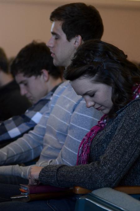 Kaitlyn Pindak (front), freshman music education major, and other students bow their heads during prayer after a message from Harry Reeder in chapel.  - Photo by Anne Richoux