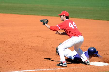 Will Irvin waits for a throw as the runner dives back to first base during a double-header against Taylor University. - Photo by Anne Richoux