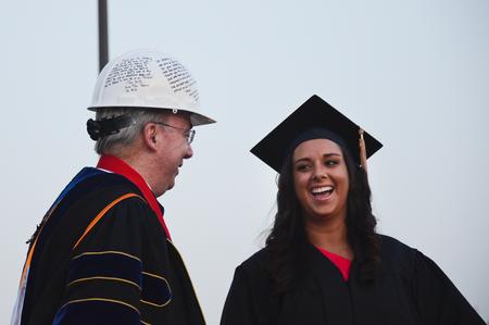 David S. Dockery, president of the university, shares a laugh with Meredith Gunn, business administration graduate and president of the senior class, as he is presented a hardhat from the class of 2012 during spring graduation. - Photo by Zac Calvert