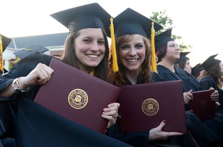 Social work graduates Courtney Allen and Courtney Burton excitedly hold up their diplomas during spring graduation.   - Photo by Anne Richoux