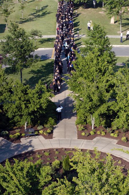 Graduates walk alongside faculty members in the processional from the PAC to the Great Lawn for spring graduation. - Photo by Kristi McMurry Woody