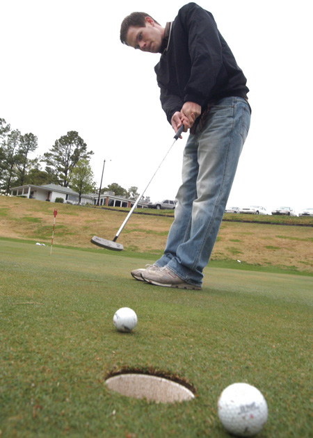 Senior Alan Baker, engineering major, practices his putting skills on an overcast weekday afternoon. - Photo by Jonathan Blair