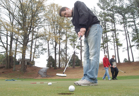 Senior Alan Baker, engineering major, practices his putting skills on an overcast weekday afternoon. - Photo by Jonathan Blair