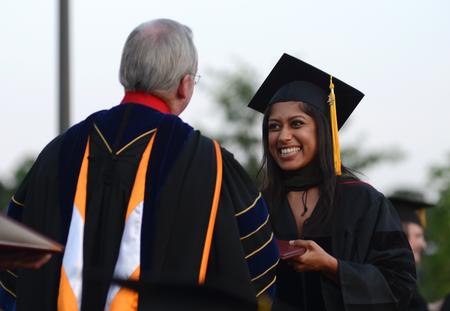 Keta Patel receives her doctor of pharmacy degree from David S. Dockery, president of the university, during spring graduation. - Photo by Jacob Moore