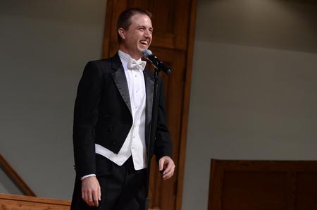 Chris Mathews, associate professor of music and department chair, laughs with the audience in between performances at the Spring Choral Concert.  - Photo by Ebbie Davis