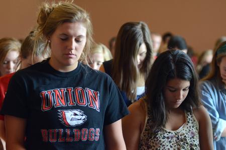 Morgan Roth, sophomore nursing major, and Alexis Pham, sophomore business administration major, join their fellow students in prayer while worshiping at chapel.  - Photo by Ebbie Davis
