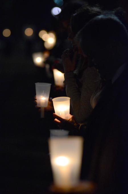 Students hold candles along the sidewalk circling Miller Tower as homicide-loss survivors walk together in remembrance of their loved ones. - Photo by Jacob Moore