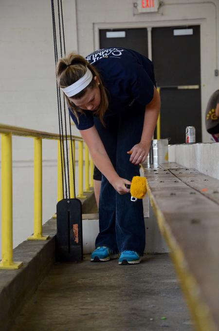 Anika Strand, senior social work major, paints the bleachers in the North Side High School gym as a part of Union's tenth annual Campus and Community Day.  - Photo by Anne Richoux
