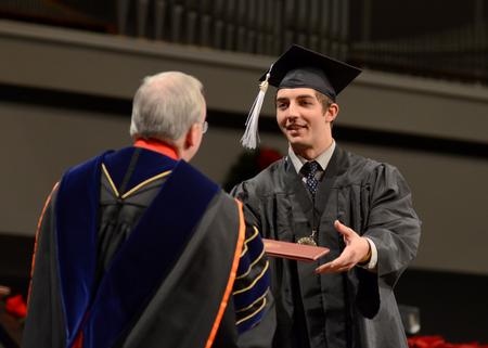 Jordan Norton, broadcast journalism graduate, accepts his diploma from David S. Dockery, president of the university, during Fall Commencement. - Photo by Jacob Moore