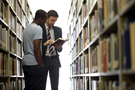Jason Crawford, assistant professor of English, helps a student choose a book in the library.  - Photo by Kristi McMurry Woody