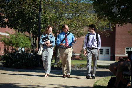 Scott Huelin, associate professor of English and director of the honors community, walks across campus with students. - Photo by Kristi McMurry Woody