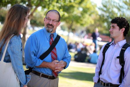 Scott Huelin, associate professor of English and director of the honors community, stops outside to chat with a couple of students. - Photo by Kristi McMurry Woody