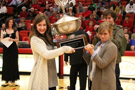 Sarah Hill and Melissa Fields, senior business administration majors, represent ENACTUS to accept the President's Cup during the Homecoming halftime events. - Photo by Matt McDaniel