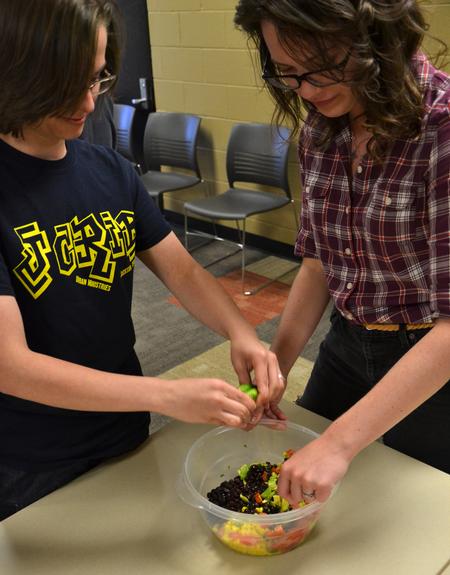 Kaitlyn Pindak, sophomore music education major, and Cameron Wilson, sophomore english major, add lime juice as the finishing touch to the southwestern black bean salad during residence life's event Cooking with Class.  - Photo by Olivia Wallace