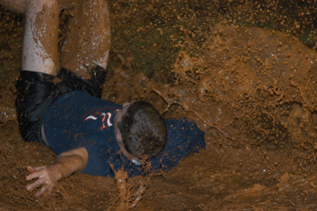 Freshman Kelly Reid dives backwards into a pool of mud during the Young Alum's Midnight Mudness. - Photo by Jonathan Blair