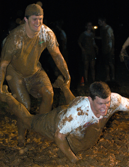 Juniors Grant Gaines and Gary Snuffin participate in the wheelbarrow race during the Young Alum's Midnight Mudness. - Photo by Jonathan Blair