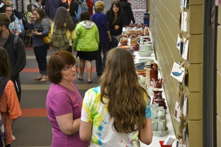 Vanessa Jackson, mail services assistant, chats with one of the artists at the annual Mother's Day pottery sale.  - Photo by Olivia Wallace