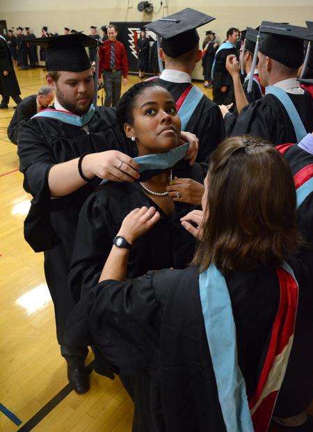 Candace Obadina receives help from fellow master of urban education graduates in getting her robe and hood in place before Spring Graduation. - Photo by Jacob Moore
