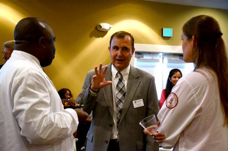 David Kuhl, Baptist Memorial Health Care Professor of Pharmacy, talks with Joseph M. Mburu, doctor of pharmacy class of 2015, and Heather Todd, doctor of pharmacy class of 2015 at the reception for the sixth annual white coat ceremony. - Photo by Amanda Rohde