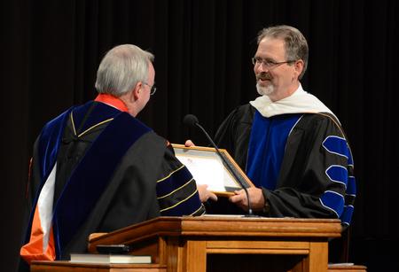 David Dockery, president of the university, formally installs John Netland, professor of English, as the dean of the College of Arts of Sciences during convocation. - Photo by Jacob Moore
