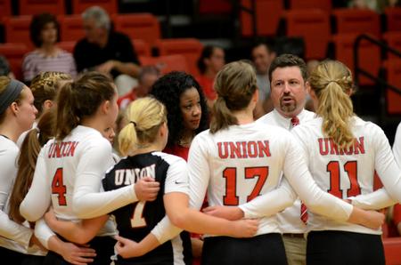 The volleyball team huddles Kim Wade, assistant coach, and Tripp Swisher, head coach, during their game against Harding University in the Fred Delay Gymnasium. - Photo by Anne Richoux