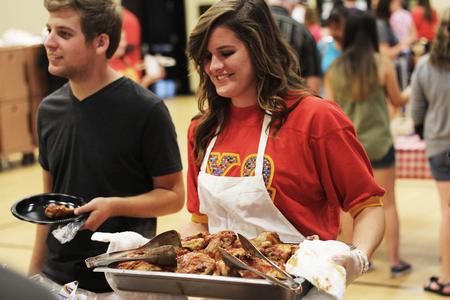 Kenzie Carter, senior art major, sets out the barbecued chicken at the Chi Omega barbecue for the for their philanthropy, Make a Wish Foundation. - Photo by Matt McDaniel