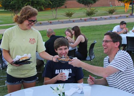 Sydney Jensen, freshman nursing major, picks up plates at the Chi Omega barbecue fundraiser for Make a Wish Foundation. - Photo by Matt McDaniel